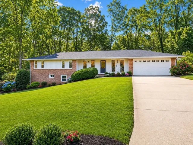 Ranch-style residence featuring a brick facade, white siding, and a dark shingle roof