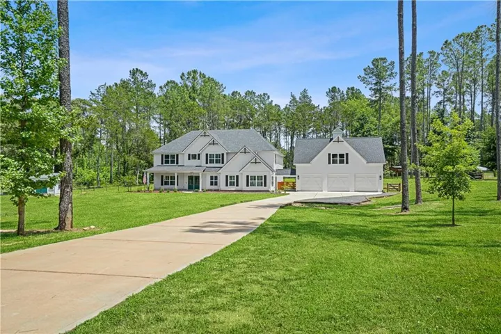 White exterior with dark shutters, covered front porch, and an attached three-car garage