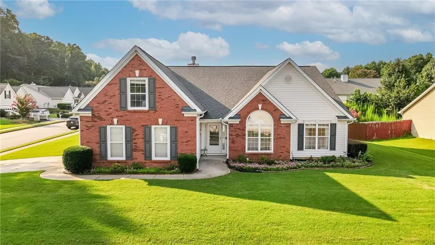 Brick and siding exterior featuring dark shutters, an arched window, and a gabled roofline