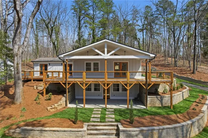 Multi-level decking with wood railings, light-toned siding, and a gabled roofline