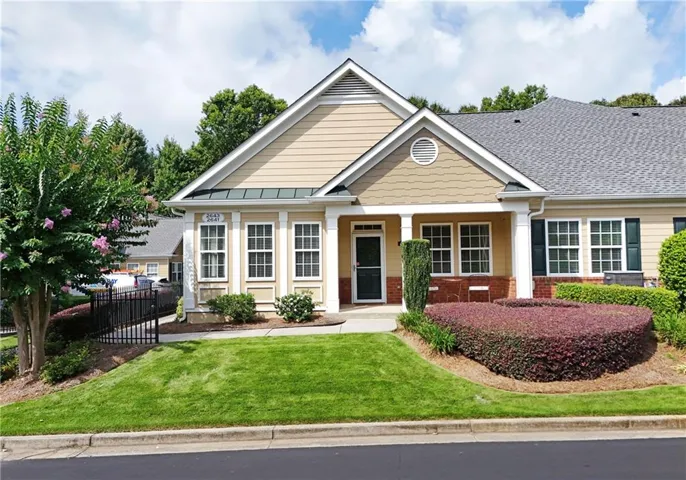 Light-colored siding exterior with a shingled roof, featuring a covered entry and a manicured lawn