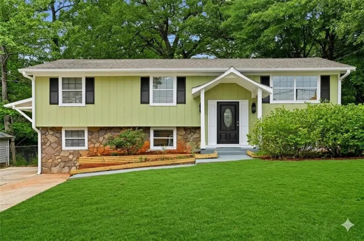 Split-level home featuring light green siding and stone veneer