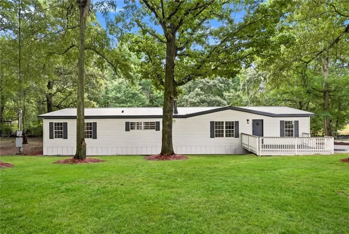 Single-story home featuring a metal roof, white siding, and dark shutters