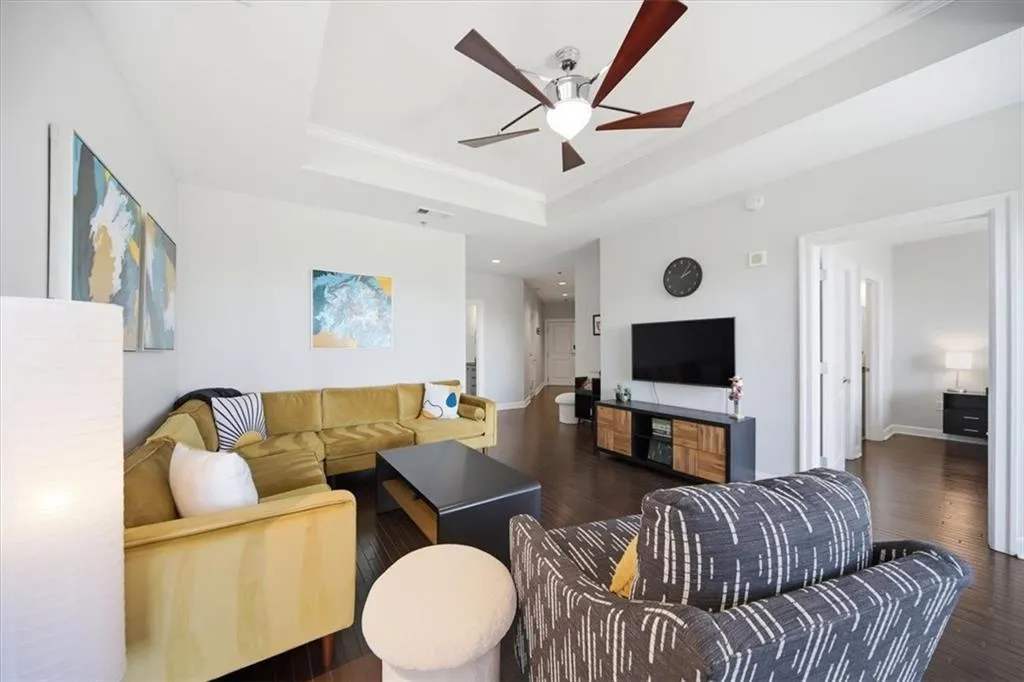 Living area with a ceiling fan, wood finished floors, and ornamental molding