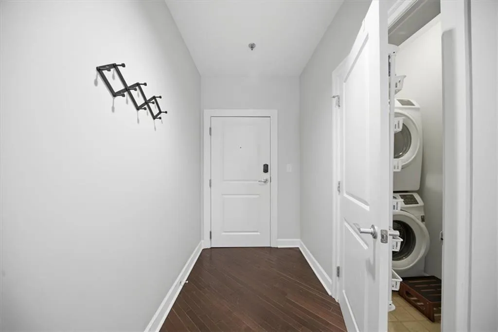 Laundry room featuring dark wood-type flooring and stacked washer and dryer