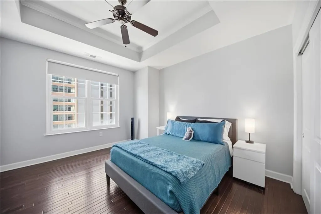 Bedroom featuring dark wood finished floors, a raised ceiling, a ceiling fan, and ornamental molding