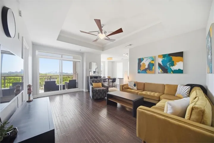 Living room featuring a ceiling fan, dark wood-style floors, and arched walkways