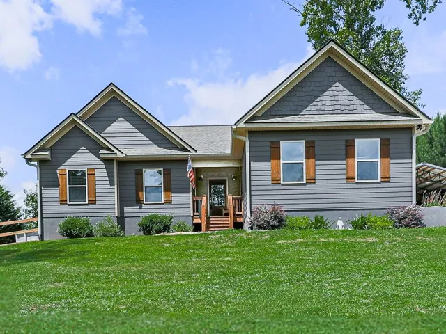 Exterior featuring gray horizontal siding and shake accents, a covered entry porch with wooden railings, and wooden window shutters