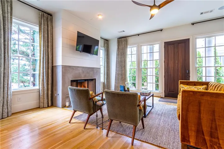 Living room with light wood-type flooring, a fireplace, and a ceiling fan