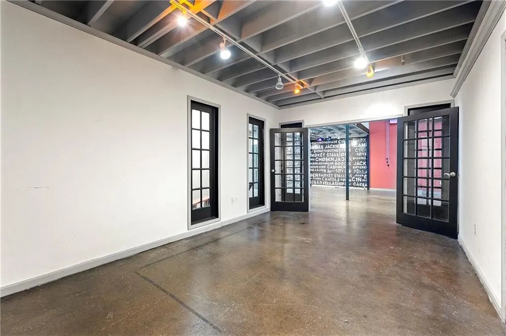 Unfurnished room with concrete floors, rail lighting, and french doors