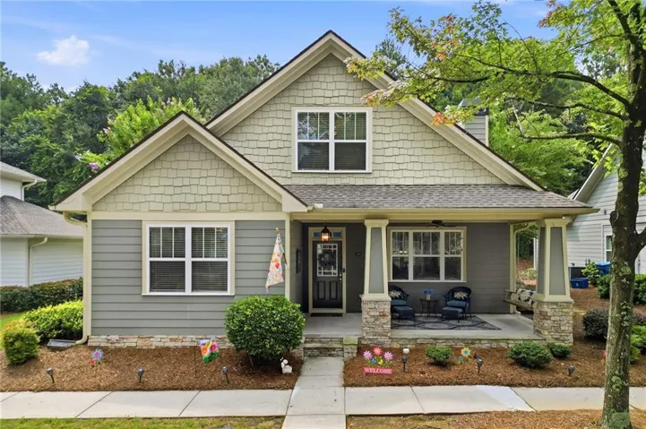 Craftsman-style exterior with a covered front porch featuring stone-clad columns, horizontal siding, and shake siding accents