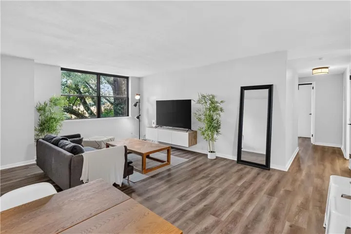 Spacious living area featuring expansive window, wood-finish flooring, and light gray wall tones