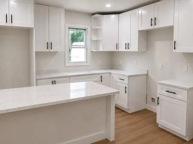 Kitchen featuring white shaker-style cabinetry, light-toned countertops, and wood-finish flooring
