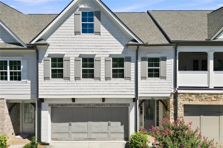 White shake siding and stone facade with gray shutters
