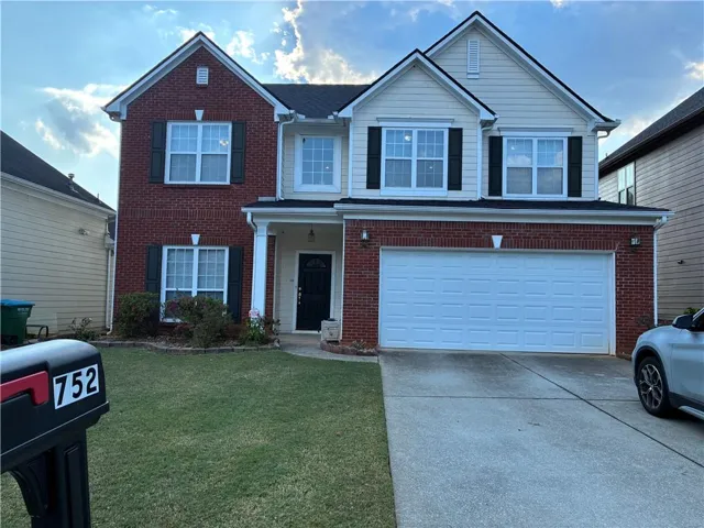 Two-story residence featuring a brick and siding exterior, a two-car garage, and a covered front entry