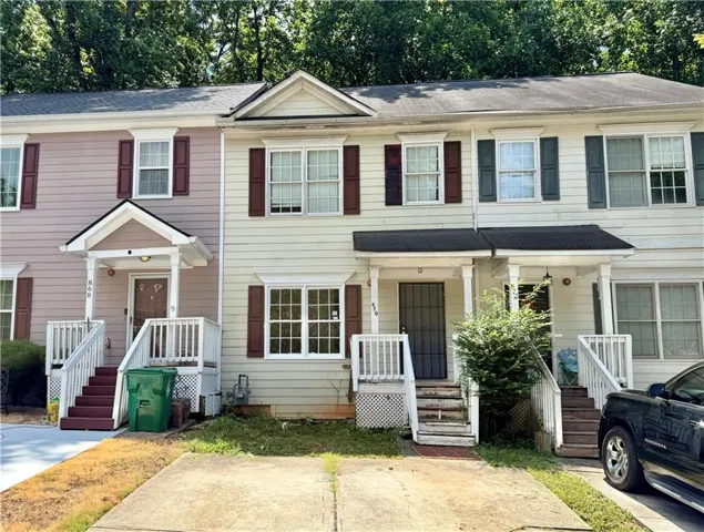 Multi-level townhome exterior featuring siding, white trim, and contrasting shutters