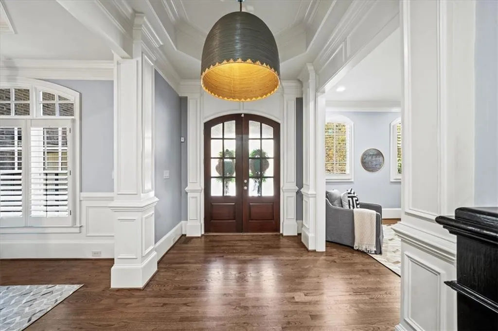 Entrance foyer featuring ornamental molding, dark wood finished floors, french doors, decorative columns, and a decorative wall