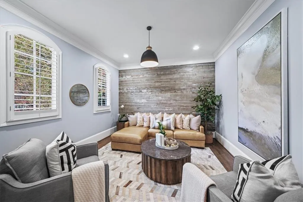Living room with crown molding, wood finished floors, an accent wall, wooden walls, and recessed lighting