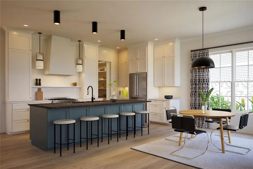 Kitchen with a kitchen bar, pendant lighting, a center island with sink, light wood-style floors, and two tone cabinetry
