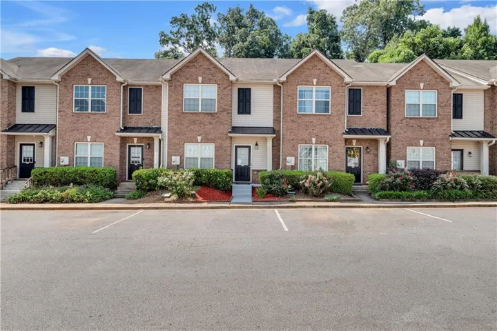 Brick exterior with contrasting siding accents, dark shutters, covered entryways, and planted landscaping