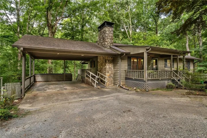 Exterior featuring a stone chimney, covered carport, and covered porch with railing