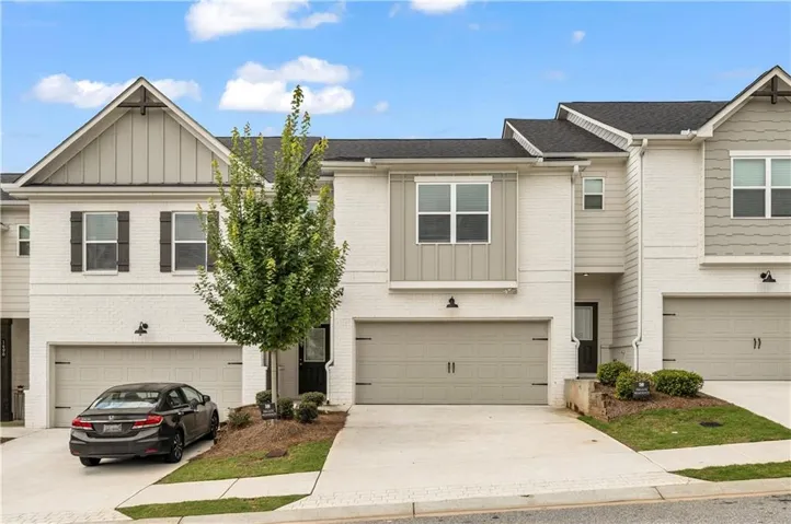 White brick exterior with board and batten accents, double garage, and paved driveway