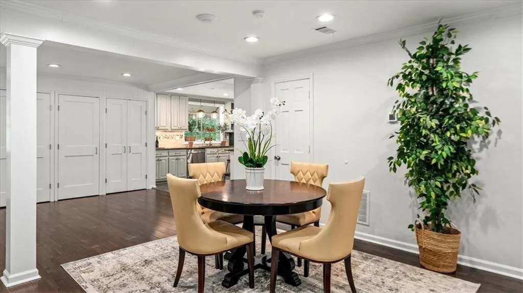 Dining room featuring decorative columns, hardwood flooring, and crown molding.