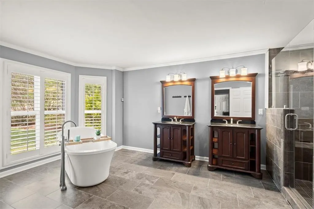 Owner's Suite Bathroom, oversized, with tile flooring, molding, dual vanities and a walk-in shower.