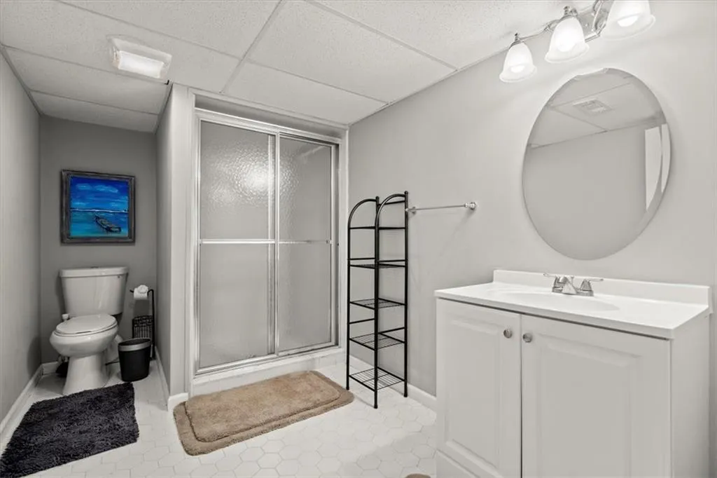 Full bath in basement features a shower with shower door, tile flooring, and vanity.