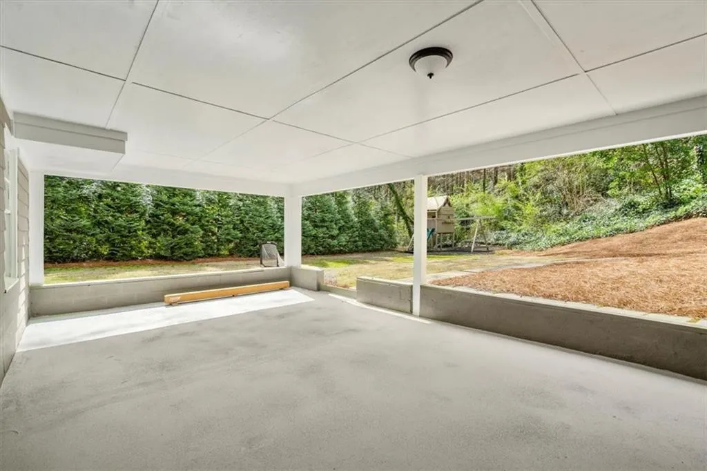 View of the terrace level patio and the level, grassy part of the backyard.  Lelands providing shade and privacy.