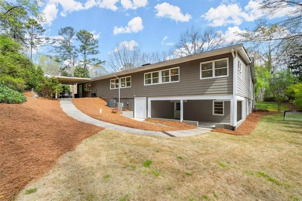 Rear view of property featuring a lawn and level area for kids to play, including swing set.