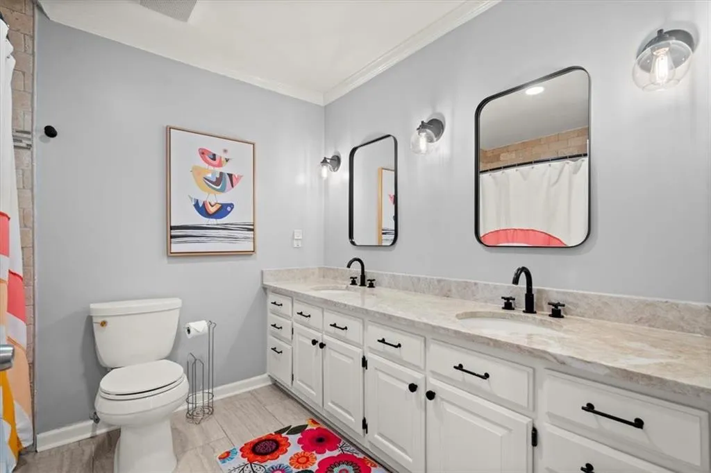 Secondary Bathroom on main level features decorative molding, dual vanities and new plumbing fixtures.