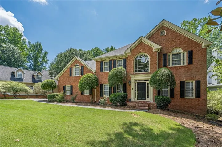 Traditional brick exterior with black shutters and a prominent arched window above the entry