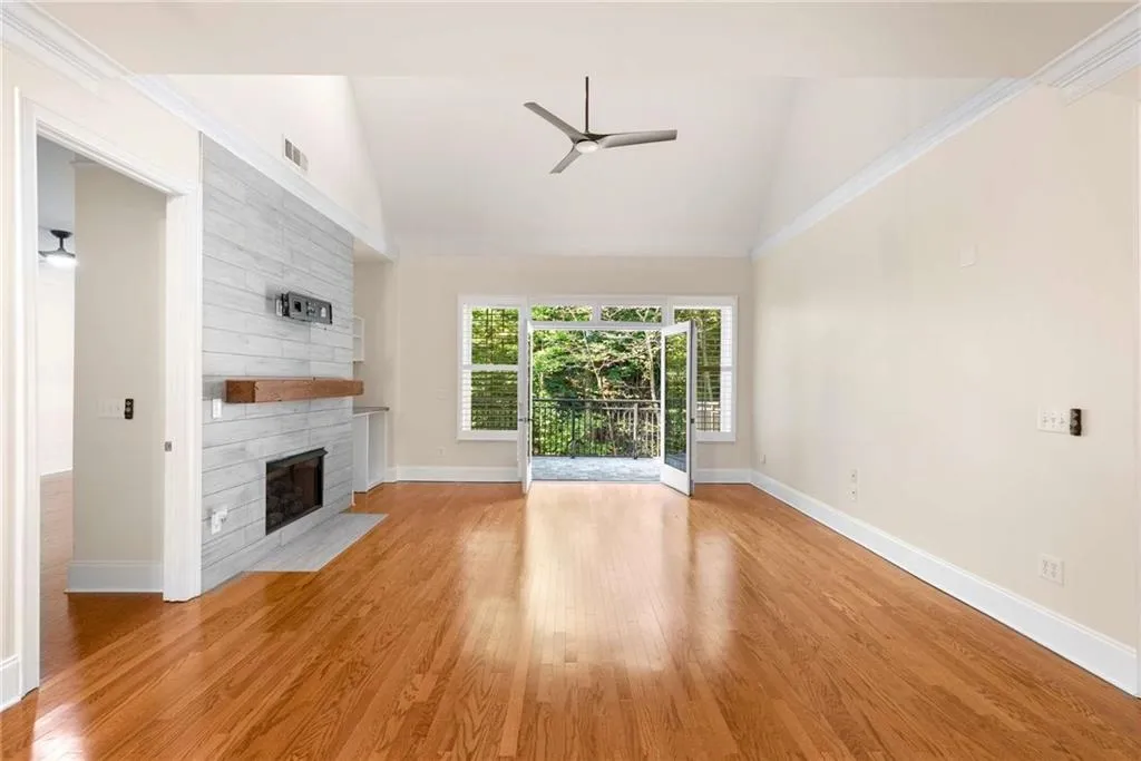 This view shows the high vaulted ceiling, gas logs fireplace with the updated surround, mantle and television  mount.  The open doors to the private balcony have views of Vinings Mountain.  Nothing can ever be built to spoil this natural view.