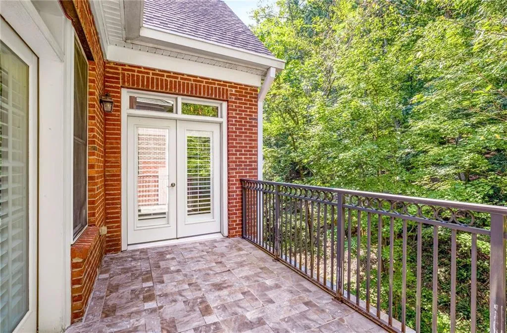 The private balcony with woods view and doors to the Primary Bedroom.