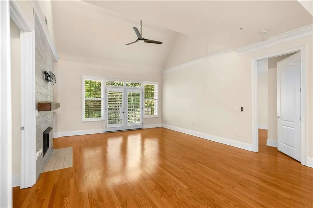 You will quickly notice the high-end finishes you would expect in a luxury condominium: wood and solid surface floors, high ceilings (typically 10 feet), 8 feet tall doors, deep rich moldings for the crown, base, doors and windows, custom plantation shutters. large windows and glass doors and upgraded lighting and ceiling fans.The door on the right is partially open to the main level Secondary Bedroom and the door on the left to the Primary Suite.
