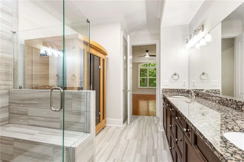 Bathroom featuring double vanity, ornamental molding, a shower stall, and a ceiling fan