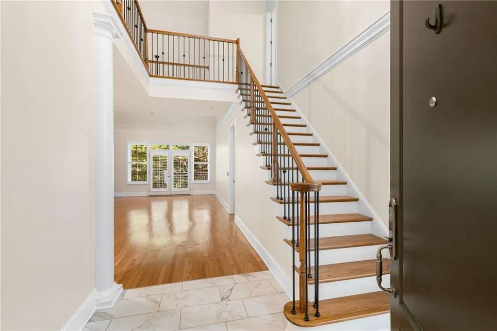 The entry view of Suite 410 with beautiful floors leading to the living room and private balcony beyond the glass French doors.  The stairway leads to the second level of this wonderfully special townhouse.