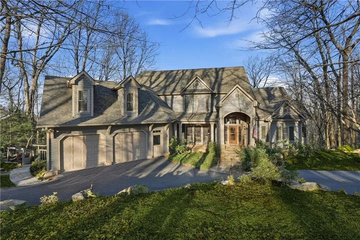 Architectural residence featuring a multi-gable roofline, dormer windows, a three-car garage, and a covered entry