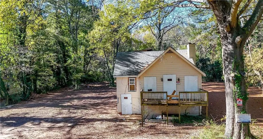 Exterior featuring a wood deck, a chimney, and a gabled roofline
