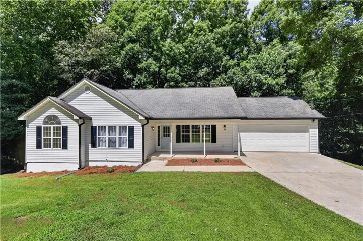 Single-story white siding residence featuring a covered front porch, an attached two-car garage, and a concrete driveway