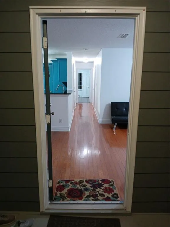 Corridor with wood-type flooring and a textured ceiling