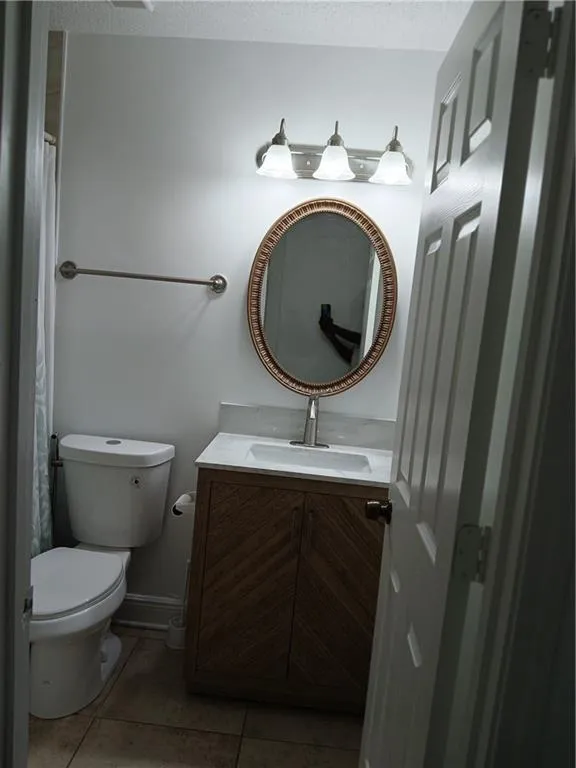 Full bath featuring vanity, light tile patterned flooring, a textured ceiling, and a shower with shower curtain