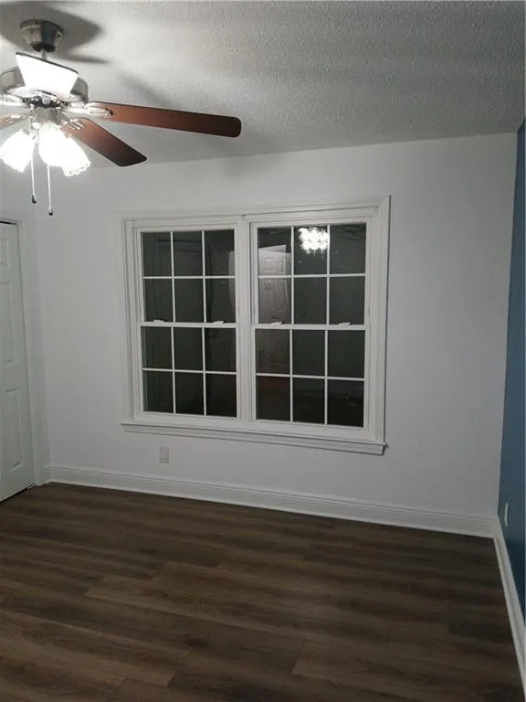 Spare room featuring a textured ceiling, dark wood finished floors, and a ceiling fan