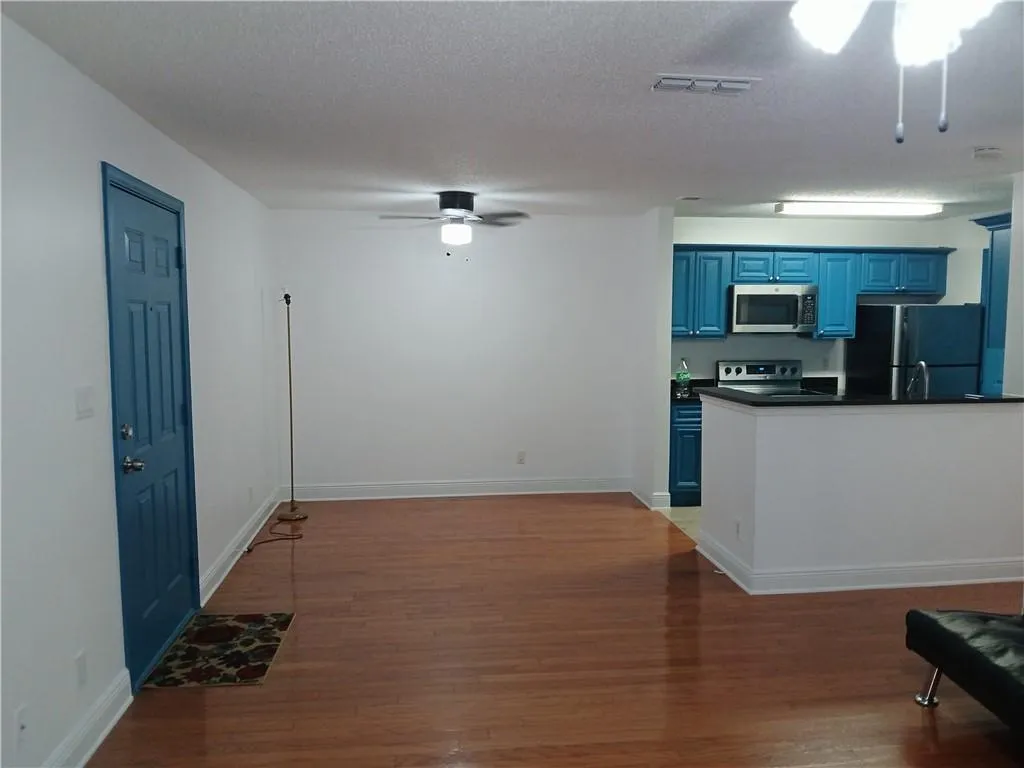 Kitchen with blue cabinets, a ceiling fan, light wood-type flooring, appliances with stainless steel finishes, and a textured ceiling