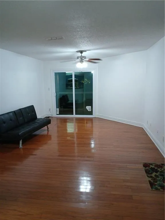 Unfurnished living room with wood-type flooring, a textured ceiling, and ceiling fan