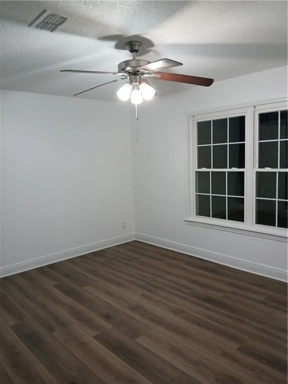 Unfurnished room with dark wood-style floors, a textured ceiling, and ceiling fan