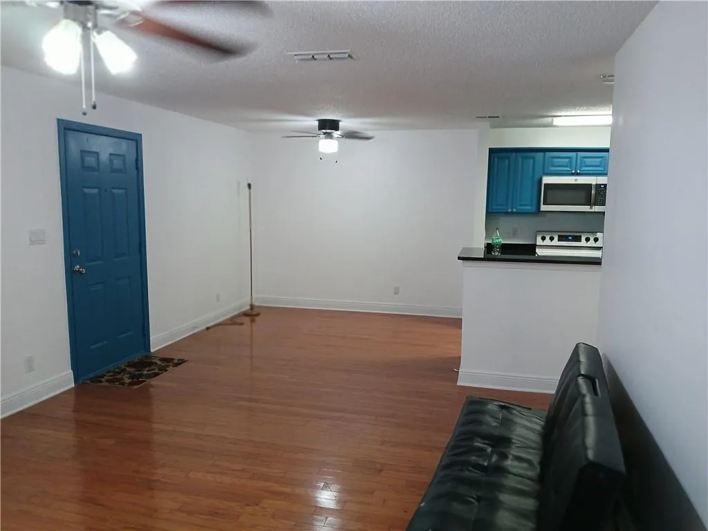 Unfurnished living room featuring dark wood finished floors, ceiling fan, and a textured ceiling