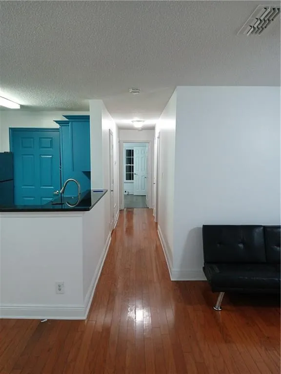 Hallway with dark wood-style flooring and a textured ceiling