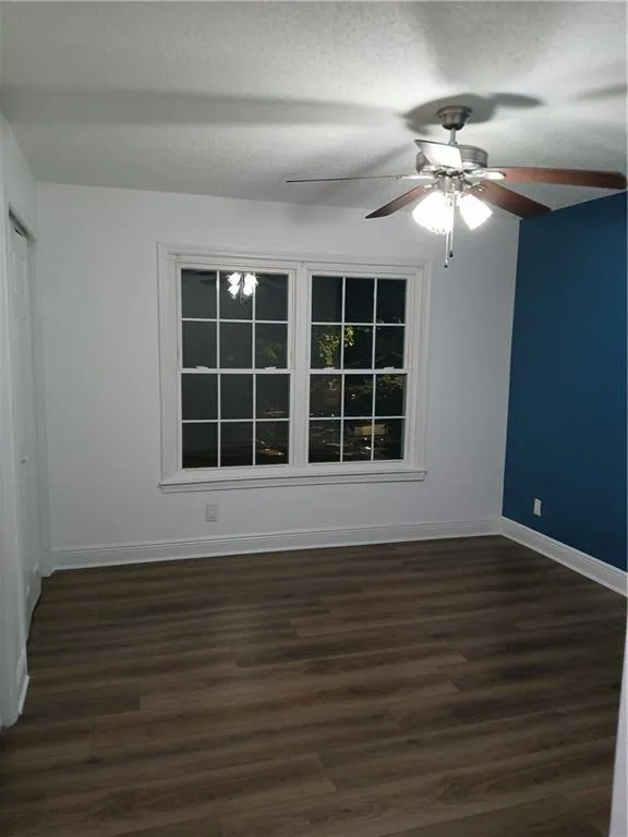 Unfurnished bedroom featuring dark wood-style floors, a ceiling fan, a textured ceiling, and a closet